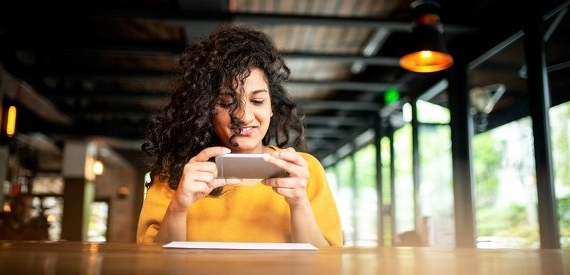 Girl taking a photo of her check to show how remote deposit capture works.